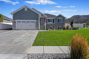 View of front of house with a garage, a front lawn, and a mountain view