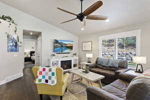 Living room with ceiling fan, dark hardwood / wood-style flooring, and vaulted ceiling