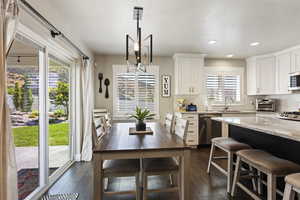 Kitchen with dark hardwood / wood-style flooring, tasteful backsplash, white cabinets, appliances with stainless steel finishes, and light stone counters