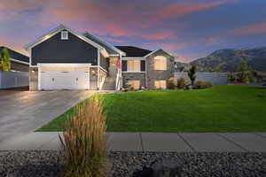 View of front facade featuring a lawn, a mountain view, and a garage