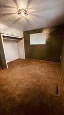 Unfurnished bedroom with carpet, a closet, and a textured ceiling