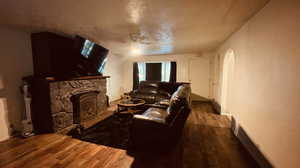 Living room with hardwood / wood-style flooring, ceiling fan, and a stone fireplace