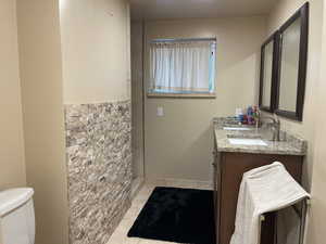 Bathroom featuring tile patterned flooring, dual bowl vanity, and toilet