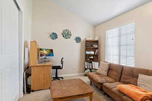 Carpeted office space featuring vaulted ceiling and a healthy amount of sunlight