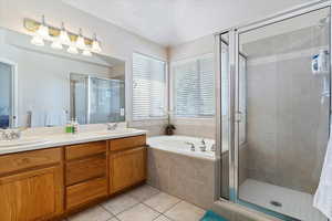 Bathroom with independent shower and bath, double sink vanity, and tile patterned floors