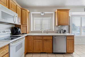 Kitchen featuring sink, white appliances, and light tile patterned floors