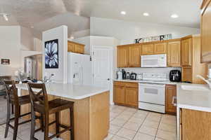 Kitchen with sink, high vaulted ceiling, white appliances, and light tile patterned floors