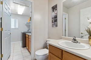 Bathroom featuring tile patterned flooring, washer and dryer, vanity, and toilet