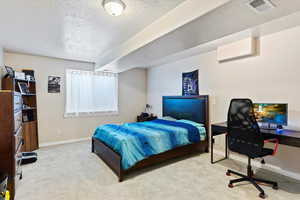 Bedroom with light colored carpet and a textured ceiling