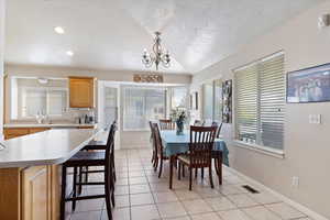 Dining area with light tile patterned floors, a textured ceiling, and a chandelier