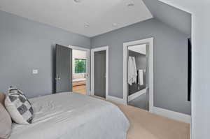 Carpeted bedroom featuring lofted ceiling and ensuite bath