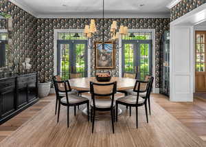 Dining room featuring french doors, light hardwood / wood-style flooring, and ornamental molding and custom wall paper