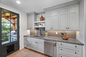 Butlers pantry with light wood-type flooring, sink, plenty of natural light, and dishwasher