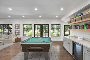 basement Rec room featuring a wealth of natural light, hardwood / wood-style floors, pool table, and beverage cooler