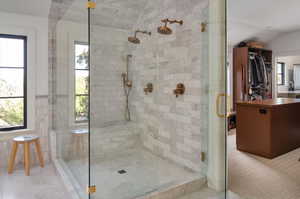 Bathroom featuring   carrara marble tile patterned floors, a shower with shower door, and a healthy amount of sunlight