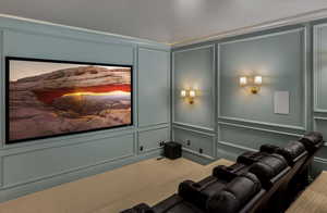 Carpeted home theater featuring crown molding