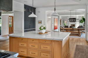 Kitchen with a center island, light brown cabinets, light hardwood / wood-style floors, and light stone countertops