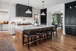 Kitchen with pendant lighting, a kitchen island, a breakfast bar, light stone counters, and hardwood / wood-style flooring