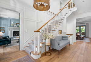 Stairway with hardwood / wood-style floors, french doors, ornamental molding, and a high end fireplace