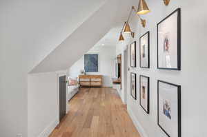 Additional living space with light wood-type flooring and vaulted ceiling