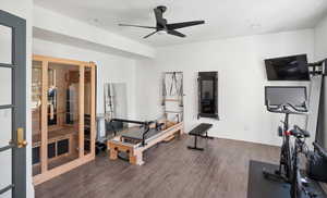 Basement exercise room with ceiling fan and dark hardwood / wood-style floors