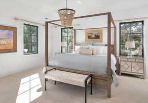 Primary Bedroom featuring an inviting chandelier, light carpet, and multiple windows