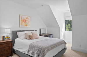 Bedroom featuring lofted ceiling and light colored carpet