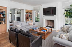 Living room featuring light hardwood / wood-style flooring, crown molding, and built in features