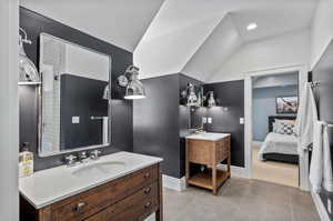 jack and jill Bathroom with tile patterned floors, vanity, and lofted ceiling