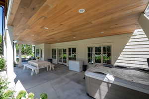 View of patio with french doors from walk out basement and a hot tub