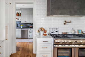 Kitchen featuring appliances with stainless steel finishes, sink, light wood-type flooring, and tasteful backsplash