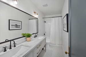 basement Full bathroom featuring tile patterned floors, double vanity, shower / bath combination with curtain, and toilet