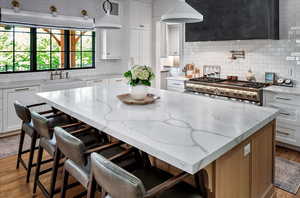 Kitchen featuring a center island, tasteful backsplash, white cabinetry, and range with gas stovetop 6 burners and griddle