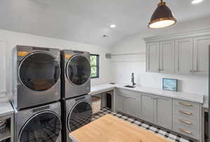 Washroom featuring sink, stacked washer and dryer, light wood-type flooring, cabinets, and washing machine and clothes dryer