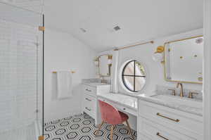 Bathroom featuring tile patterned flooring, double sink vanity, a tile shower, and lofted ceiling