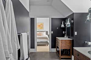 Bathroom with tile patterned flooring, vanity, and lofted ceiling