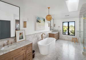 Bathroom featuring carrara marble  walls, tile patterned flooring, a bathtub, and vanity