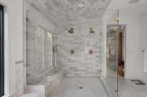 Bathroom featuring tile p carrara marble atterned floors and walk in shower