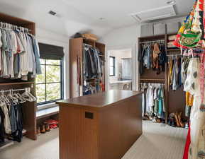 Spacious primary closet with vaulted ceiling and light colored carpet