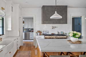 Kitchen featuring a breakfast bar, light hardwood / wood-style floors, pendant lighting, and white cabinetry