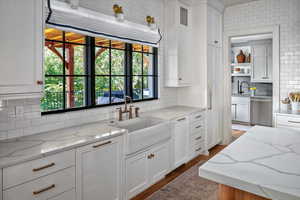 Kitchen with sink, light stone countertops, stainless steel dishwasher, and tasteful backsplash