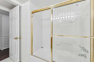 Bathroom featuring combined bath / shower with glass door and wood-type flooring