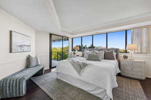 Bedroom with access to outside, crown molding, dark hardwood / wood-style flooring, and a tray ceiling