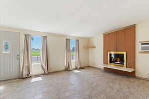 Unfurnished living room featuring brick wall, light tile patterned flooring, an AC wall unit, and a tile fireplace