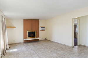 Unfurnished living room with light tile patterned floors, a wall mounted air conditioner, brick wall, and a fireplace