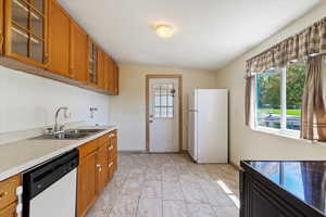 Kitchen with sink, plenty of natural light, white appliances, and light tile patterned floors