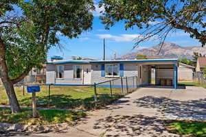 View of front of home with a front lawn, a carport, and a mountain view