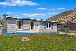 Rear view of property featuring a lawn and a mountain view