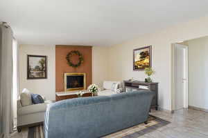 Living room featuring brick wall, tile patterned flooring, and a fireplace. *Virtually staged.