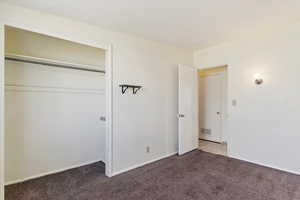 Unfurnished bedroom featuring light carpet and a closet